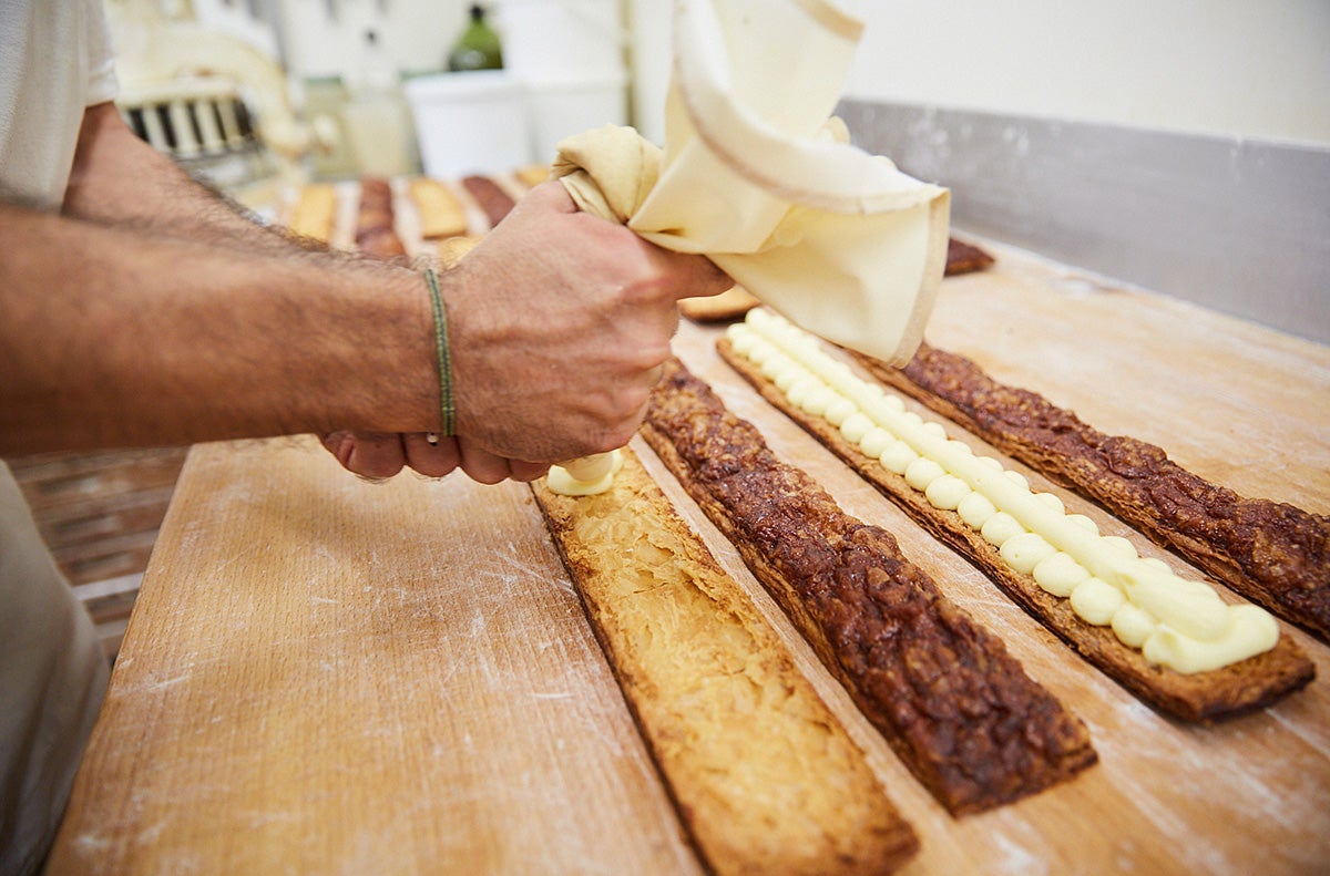Rellenando de crema pastelera las famosas cocas de crema de la casa. Rellenando de crema pastelera las famosas cocas de crema de la casa.