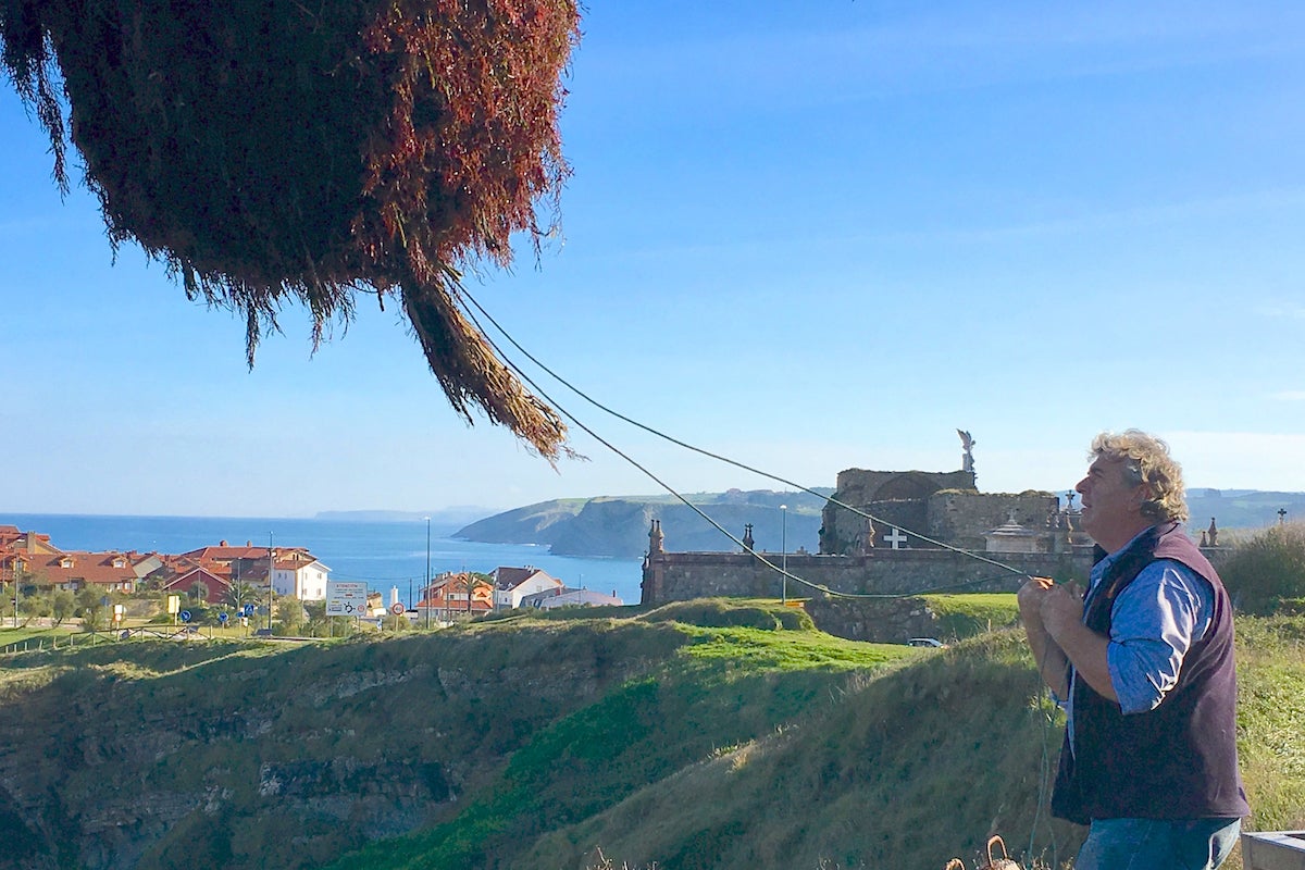 Juan vacía una cesta de “caloca” en la pluma de Comillas, con el cementerio y su Ángel Exterminador de fondo. Juan vacía una cesta de “caloca” en la pluma de Comillas, con el cementerio y su Ángel Exterminador de fondo.
